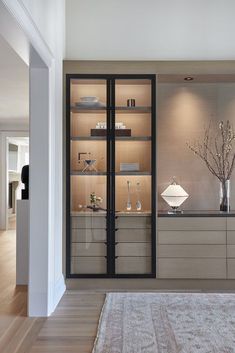 an empty living room with glass shelves and vases on the wall, along with a rug