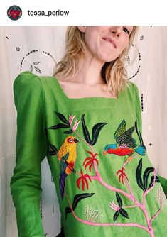 a woman wearing a green top with birds on it