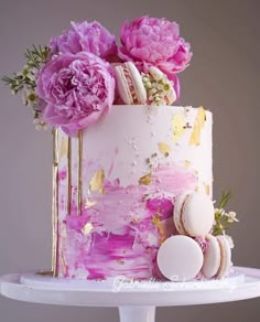 a pink and gold cake with flowers on top