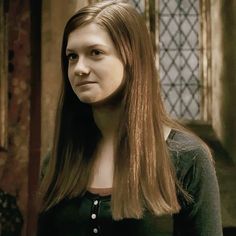 a woman with long hair standing in front of a window