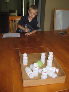 a young boy sitting at a wooden table with cups in front of him