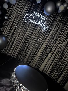 a black table topped with lots of balloons and a happy birthday sign on top of it