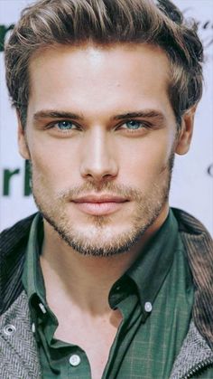 a close up of a person wearing a green shirt and looking at the camera with a serious look on his face