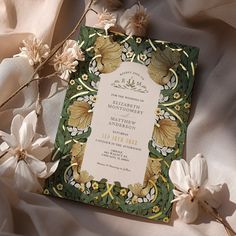 the wedding card is surrounded by flowers and satin material, with an elegant design on it