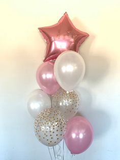 a bunch of balloons in the shape of a star are hanging from a white wall