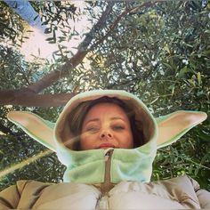 a woman in a star wars yoda mask is looking up at the camera with her eyes closed