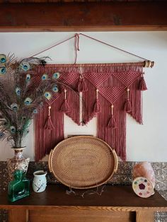 a table topped with a basket next to a peacock feather wall hanging on a wall