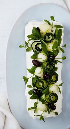 a white plate topped with cucumbers and green leaves on top of it's side