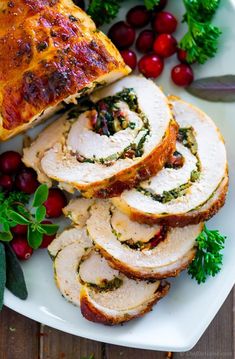 sliced turkey breast on a plate with cranberry sauce and fresh herbs next to it