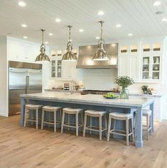 a large kitchen island with stools in the center and lights hanging from the ceiling