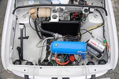 the engine compartment of a white car with its hood open and wires attached to it