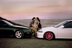 two people kissing on the hood of their cars