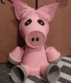 a pink pig sitting on top of a black and white checkered floor next to cardboard boxes