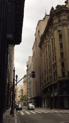 an empty city street with tall buildings on both sides and cars driving down the road