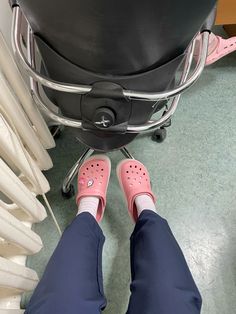 a person with pink shoes standing in front of a chair