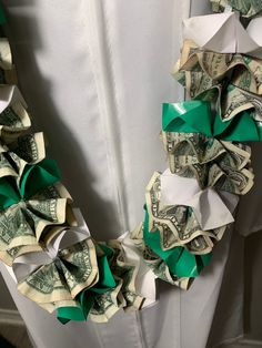 dollar bill wreath made out of rolled up bills hanging from the side of a white curtain