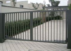 an iron gate is open on the side of a brick walkway in front of a building