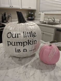 a large white pumpkin sitting on top of a kitchen counter next to a pink ball