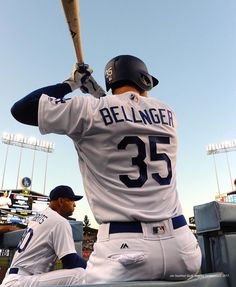 a baseball player holding a bat over his shoulder while sitting in the dugout at a game