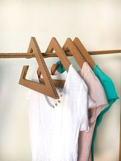 clothes hanging on wooden hangers in front of a white wall