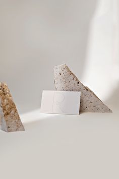 two pieces of stone with a white card on top of them, sitting next to each other