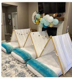 three beds with white sheets and blue pillows on top of them, in front of a tv