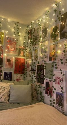 a bedroom with lots of pictures and lights on the wall above the bed, along with plants growing up the walls