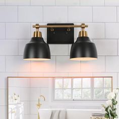 two lights are on the wall above a bathtub in a white and gold bathroom