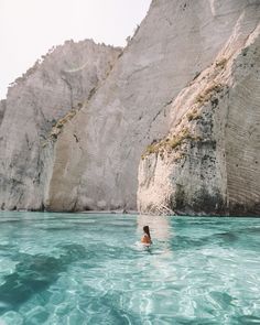 a person swimming in the ocean near some cliffs