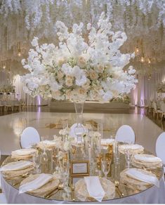 the centerpiece is surrounded by white flowers and greenery, along with gold chargers