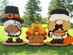 three wooden turkeys are standing in the grass with one turkey wearing a pilgrim hat