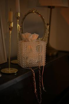 a small white purse sitting on top of a table next to a candle and mirror