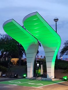 an electric vehicle charging station with green lights on the top and white curved structures above it