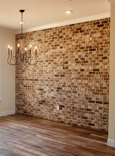 a chandelier hanging from the ceiling next to a brick wall in an empty room