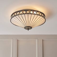 a ceiling light that is hanging from the ceiling in front of a white paneled wall