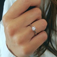 a woman's hand with a diamond ring on top of her finger, showing the side view