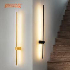 two lights that are next to each other on the wall in a room with stairs