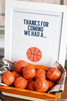 a basket filled with basketballs sitting on top of a table next to a sign