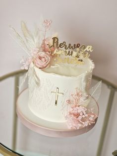 a white cake with pink flowers and a cross on top