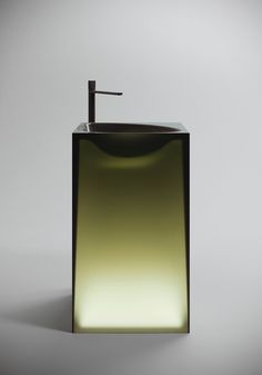 a bathroom sink with a black faucet and green tinted glass countertop, against a gray background