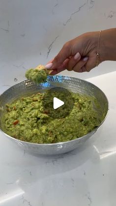 a person is dipping guacamole into a bowl