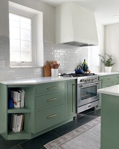 a kitchen with green cabinets and an oven in the center, along with a rug on the floor