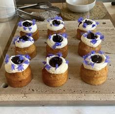 small pastries with blue and white toppings are arranged on a wooden platter