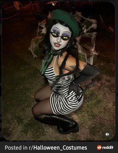 a woman dressed up as a skeleton with green eyes and black hair sitting on the ground