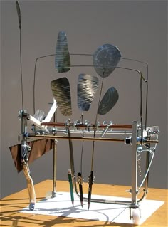 a sculpture made out of various metal objects on a wooden table next to a wall