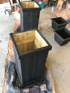 three wooden boxes sitting on top of a piece of plastic in a room filled with other items