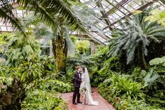 a bride and groom standing in the middle of a tropical garden