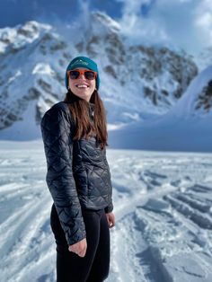 a woman standing on top of a snow covered slope wearing skis and a hat