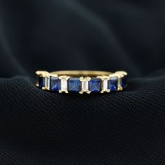 a gold ring with blue sapphires and white diamonds on black fabric, close up