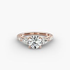 a rose gold engagement ring with three stones on the side and an accent diamond in the middle